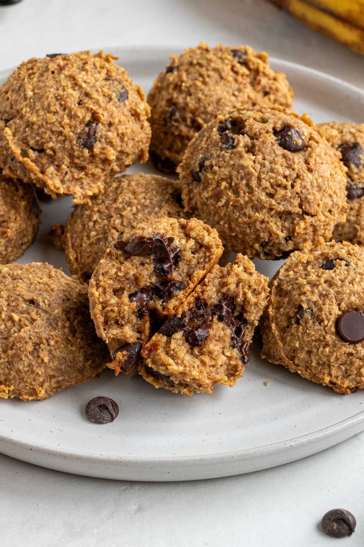 Close up of a banana bread bite broken in half with melted chocolate coming out of it on a white speckled plate.