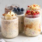 Five jars of different flavors of overnight oats on a white background.