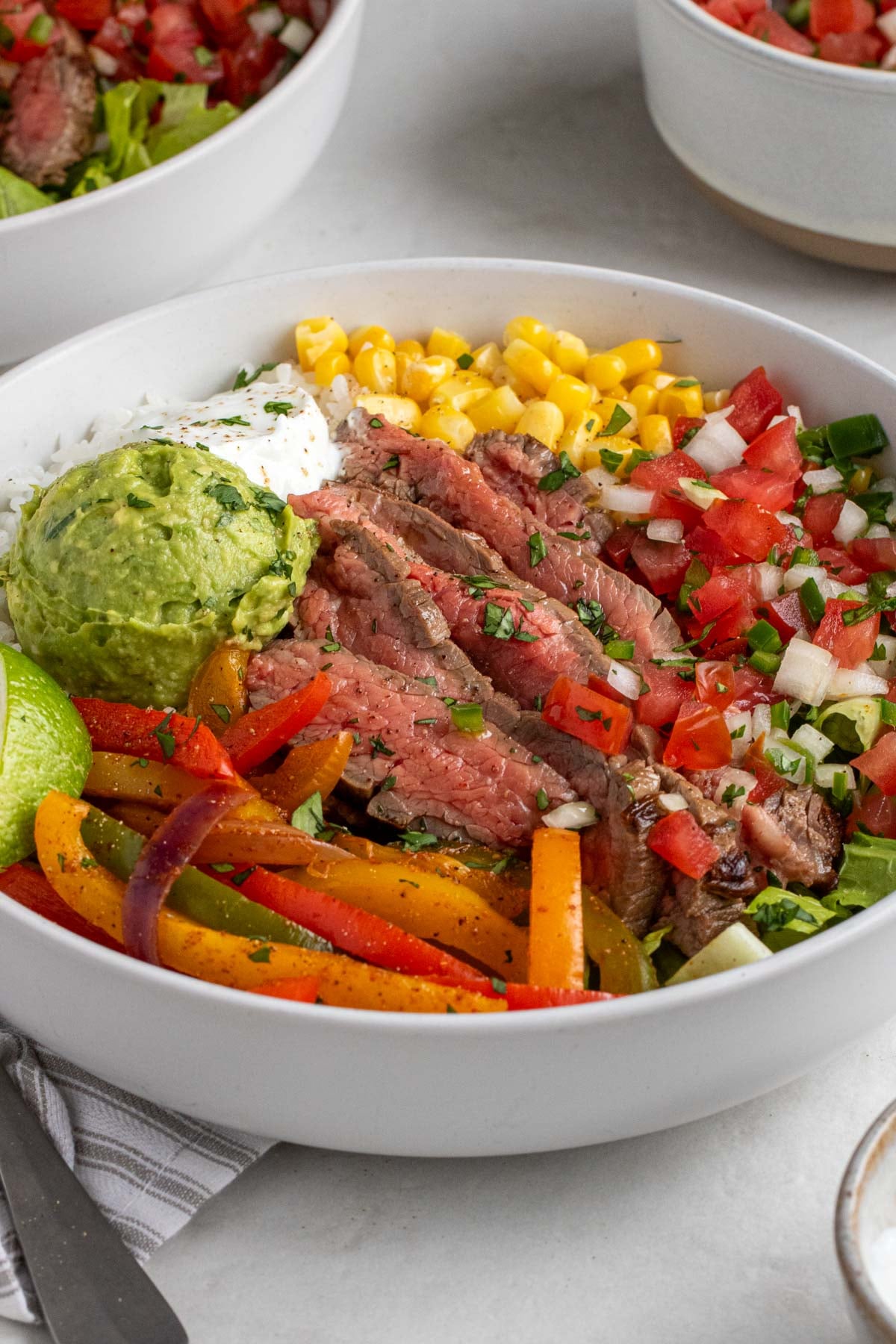 Close up of a chipotle-inspired steak fajita bowl on a white background.