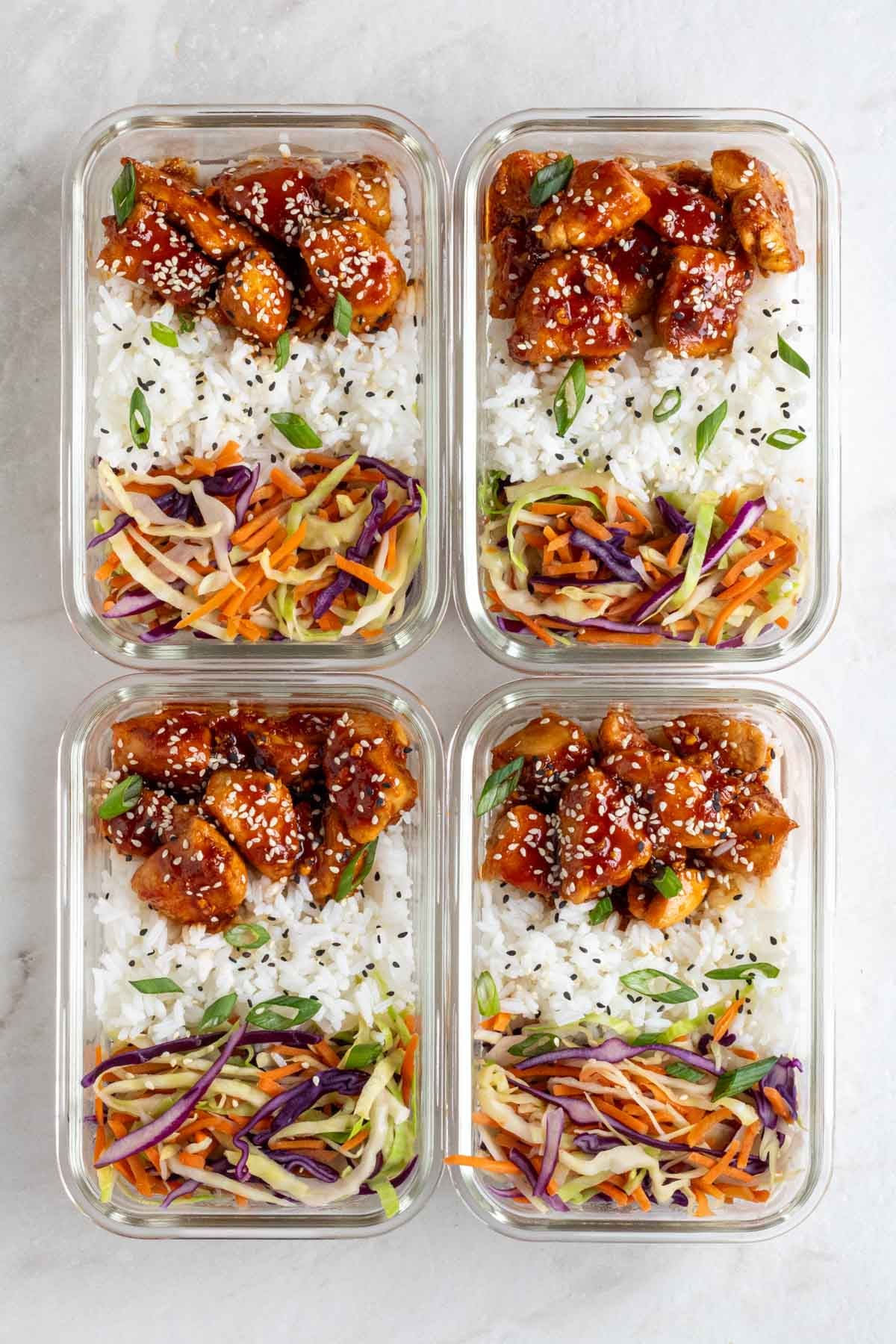 Four sticky chicken meal prep bowls in glass containers on a white background.