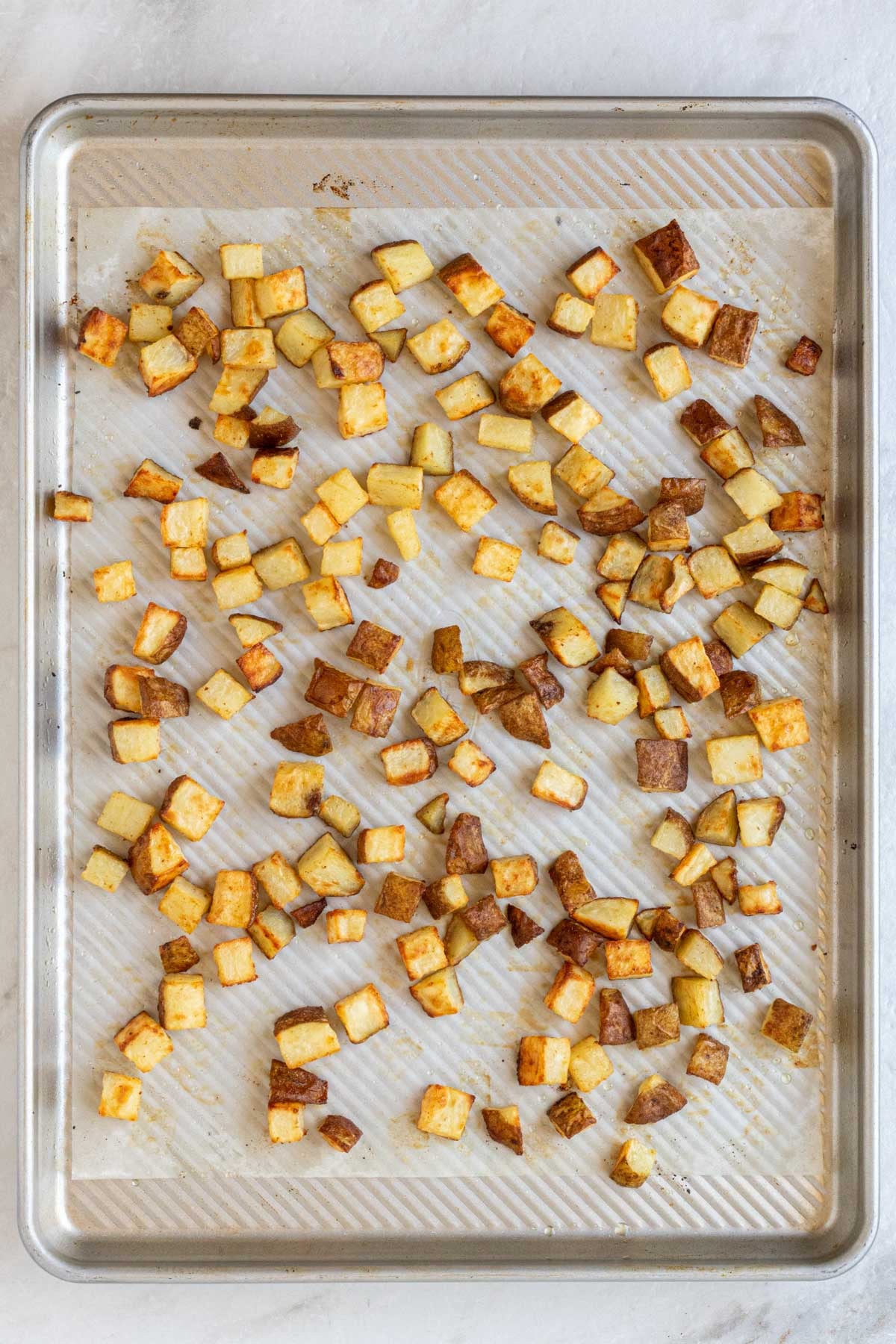 Large sheet pan with parchment paper and roasted breakfast potatoes.