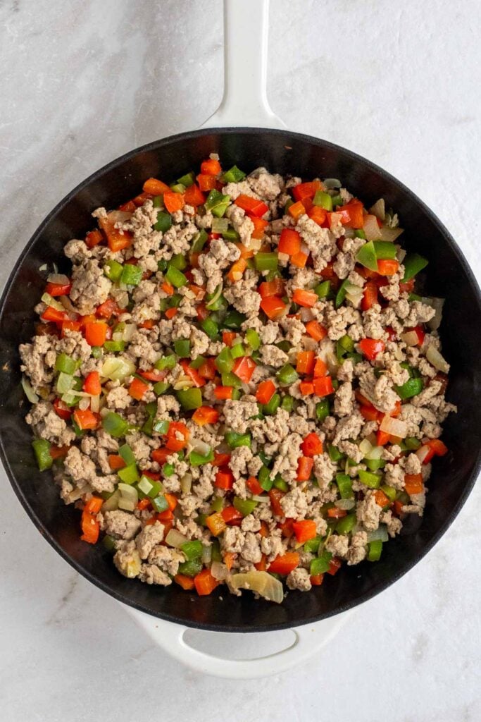 Cast-iron skillet with cooked ground turkey, onion, and bell pepper.