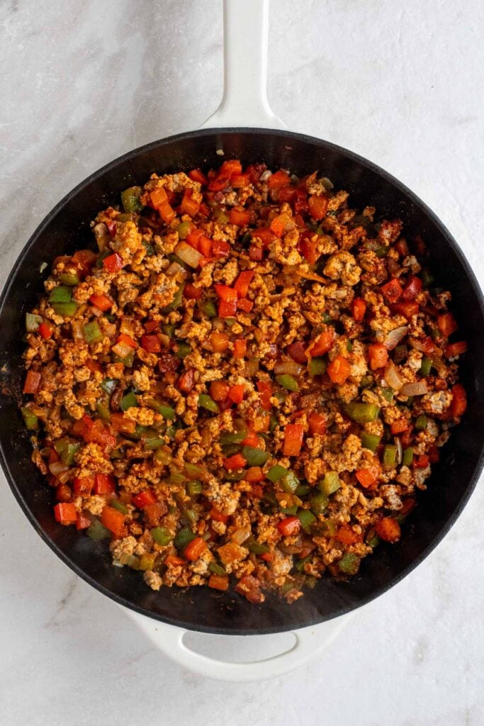 Cast-iron skillet with cooked ground turkey, onion, bell pepper, and taco seasoning.