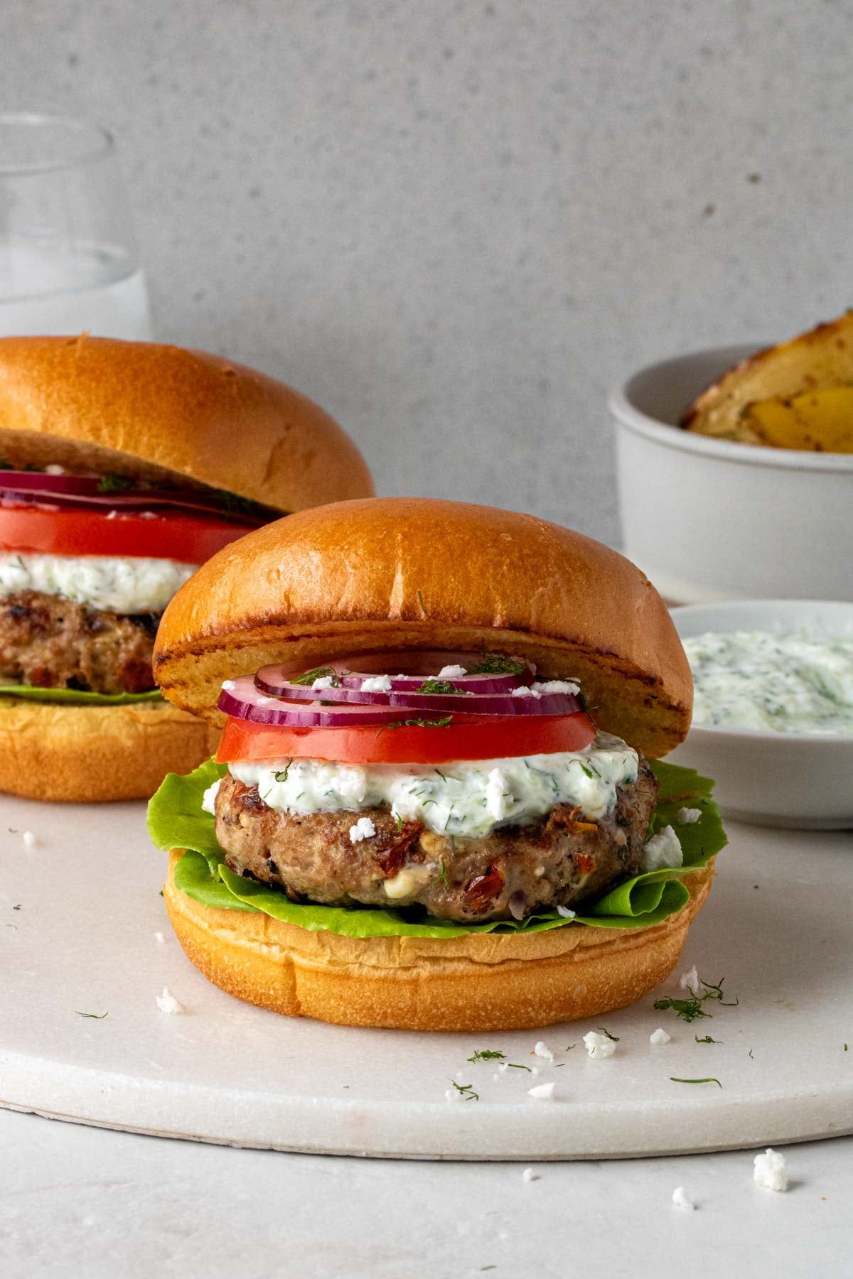 Close up of Greek ground chicken burger on a white cutting board. 