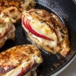 Apple and brie stuffed chicken breasts in a cast-iron skillet.