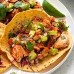 Close up of a plate of grilled salmon tacos with avocado salsa.