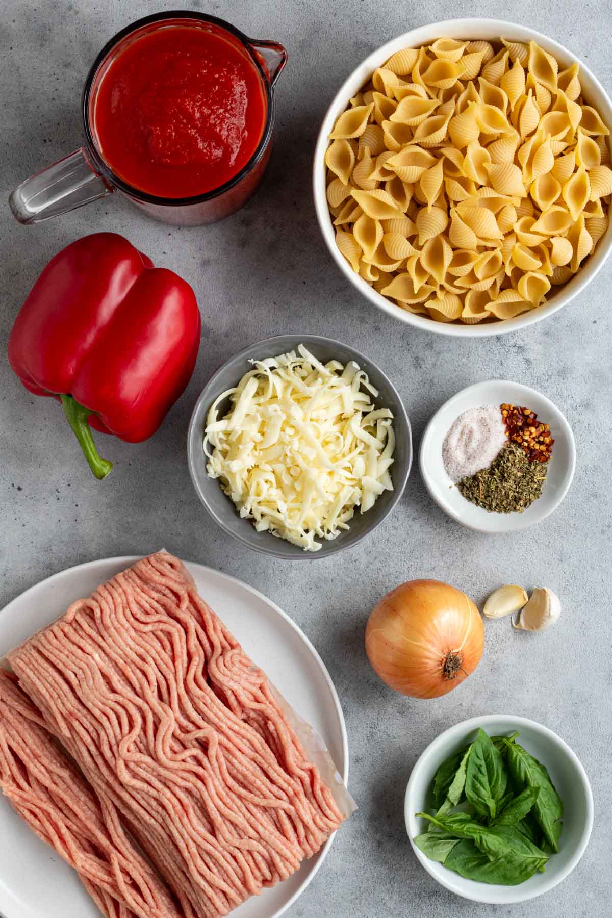 Ingredients for ground turkey baked pasta: ground turkey, shell pasta, tomato sauce, onion, garlic, red bell pepper, Italian seasoning, mozzarella cheese, salt, and pepper.