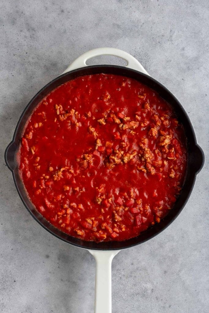 Cast iron skillet with cooked ground turkey with tomato sauce.