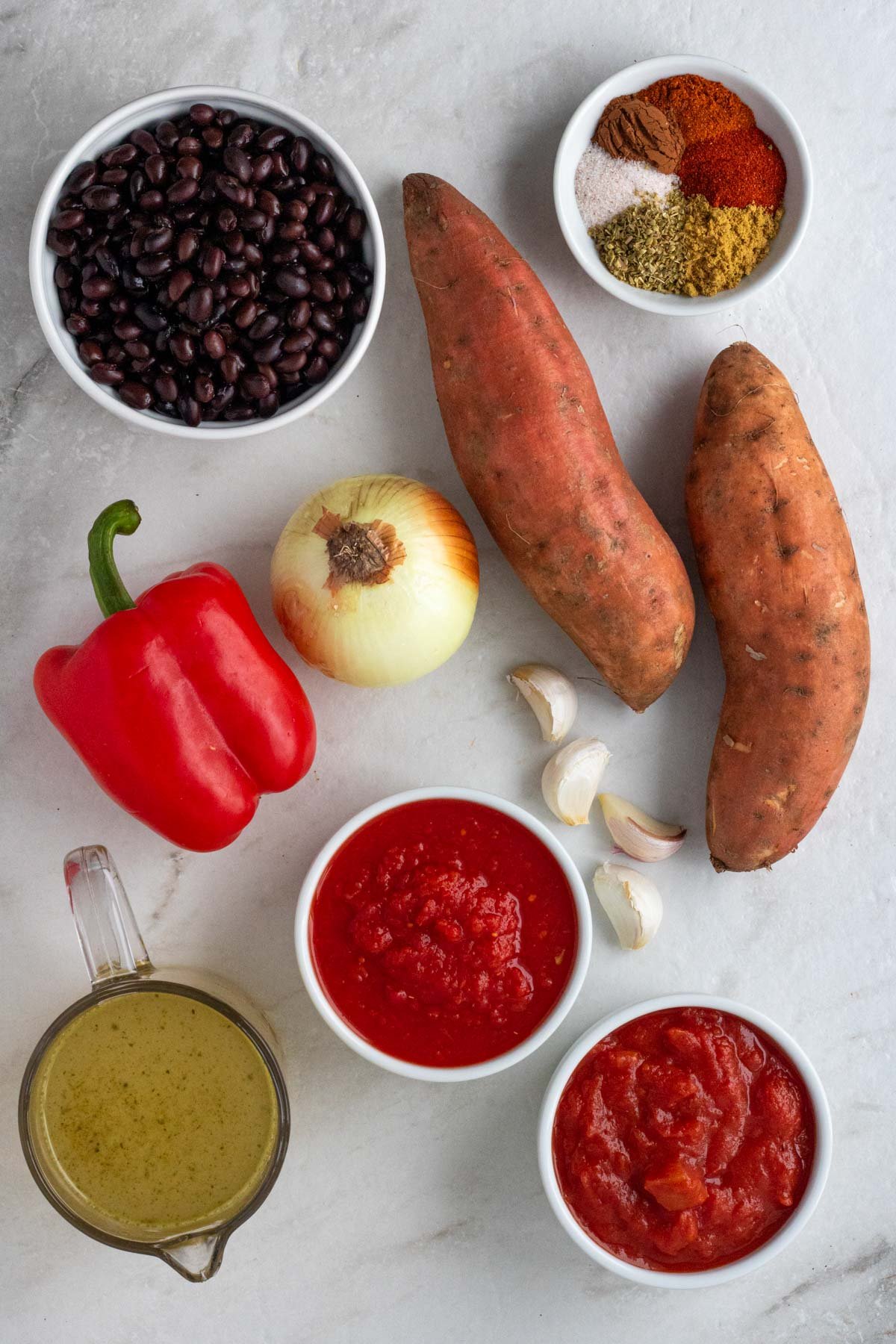 Ingredients for black bean and sweet potato chili: black beans, sweet potatoes, bell pepper, diced tomatoes, crushed tomatoes, onion, garlic, vegetable broth, chili powder, smoked paprika, cumin, oregano, salt, and black pepper.