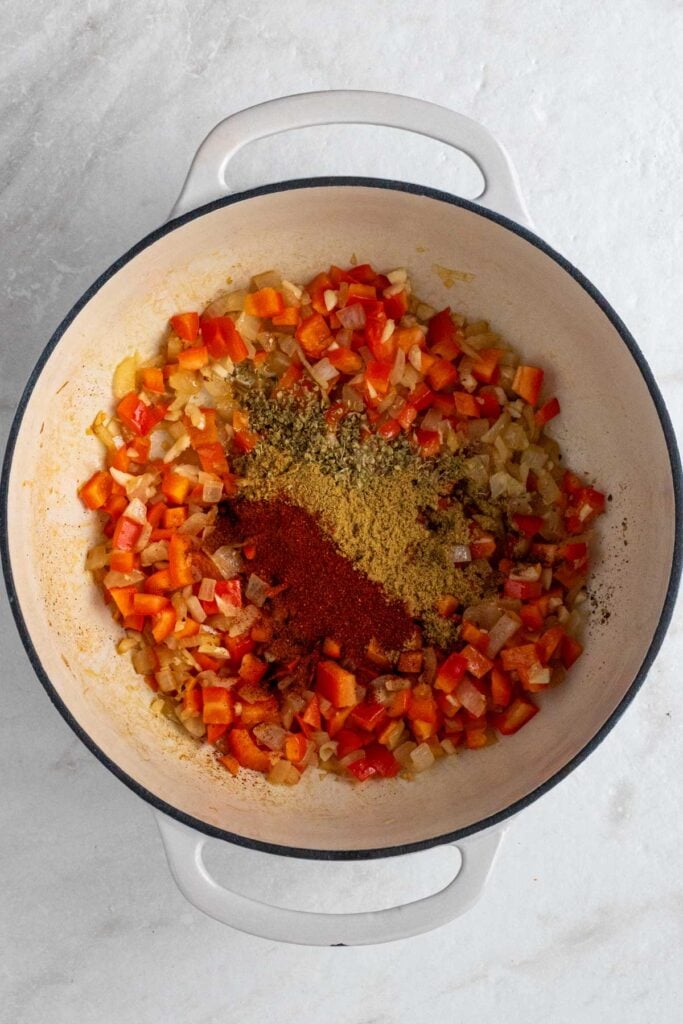 Pot with sautéed onion, bell pepper, garlic, chili powder, paprika, cumin, oregano, and salt.
