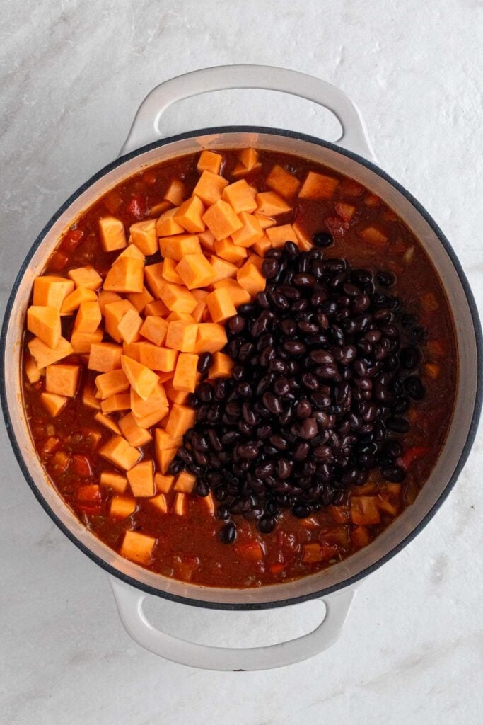 Pot with sautéed veggies, tomato sauce, black beans, and cubed sweet potatoes.
