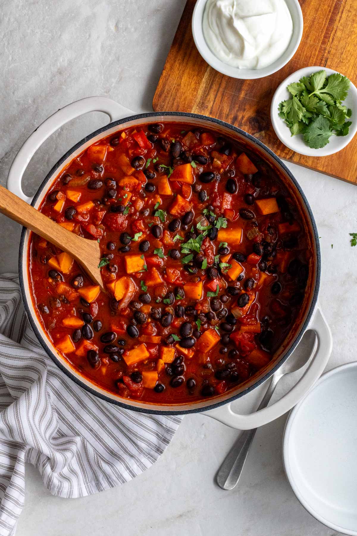 Large pot with cooked sweet potato black beans chili with fresh cilantro on top.