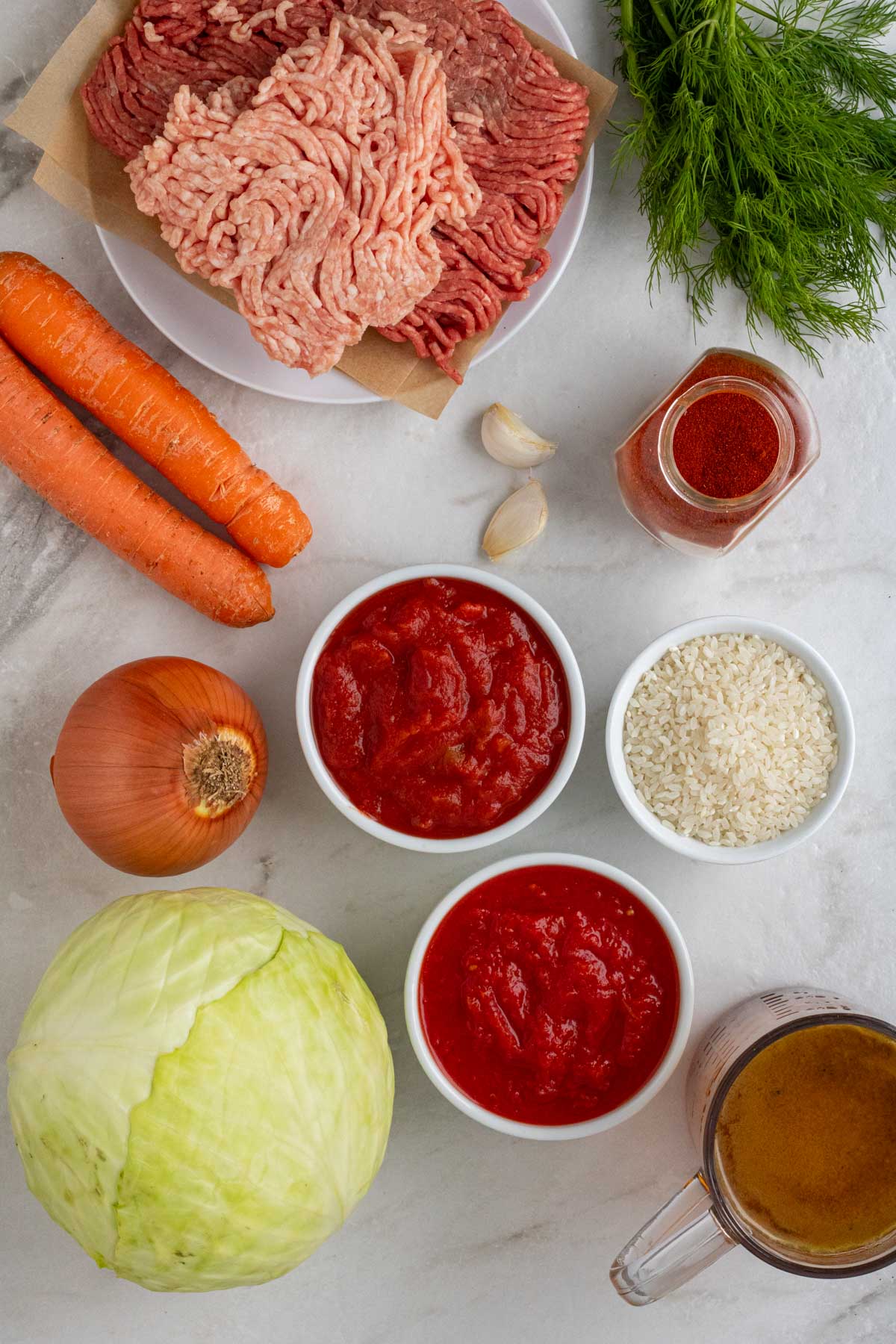Ingredients for cabbage roll soup: ground beef, ground pork, onion, garlic, carrots, cabbage, white rice, beef broth, tomatoes, paprika, dill, salt, and pepper.