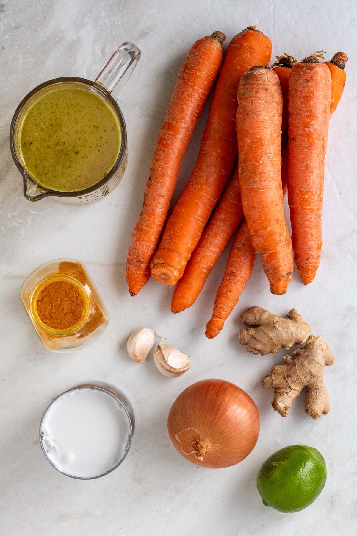 Ingredients for carrot ginger coconut soup: carrots, ginger root, garlic cloves, turmeric, coconut milk, and vegetable broth.