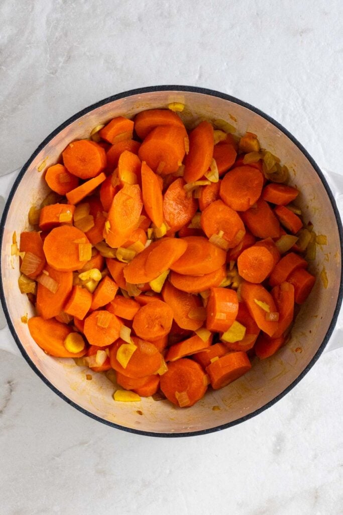 Pot with sautéed onion, chopped carrots, ginger, garlic, ground turmeric, salt, and black pepper.
