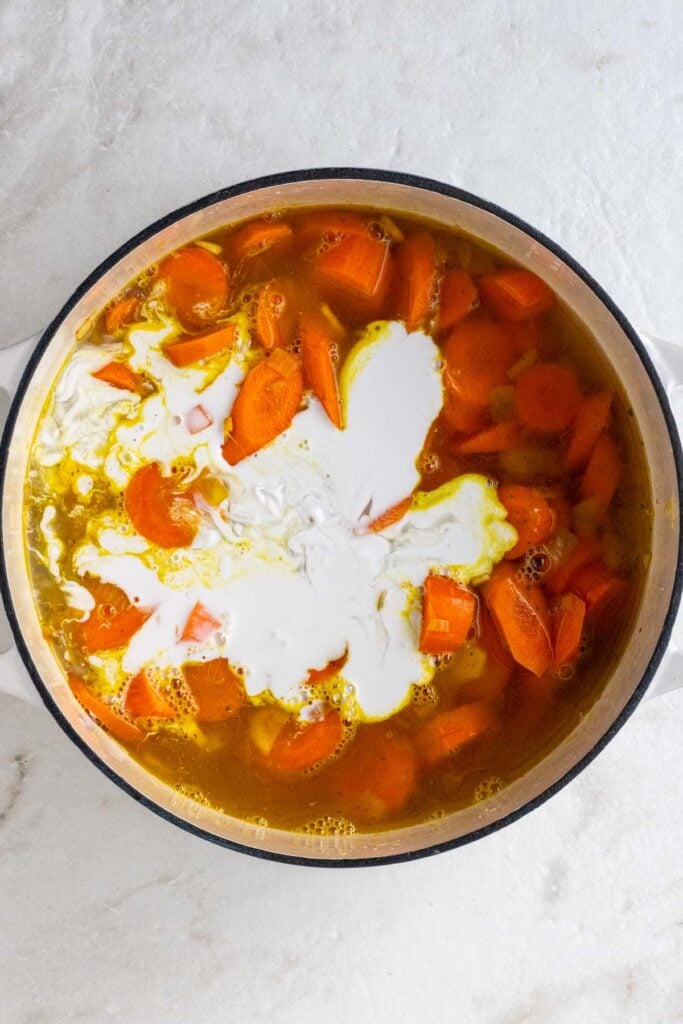 Pot oven with onions, carrots, ginger, spices, vegetable broth, and coconut milk.