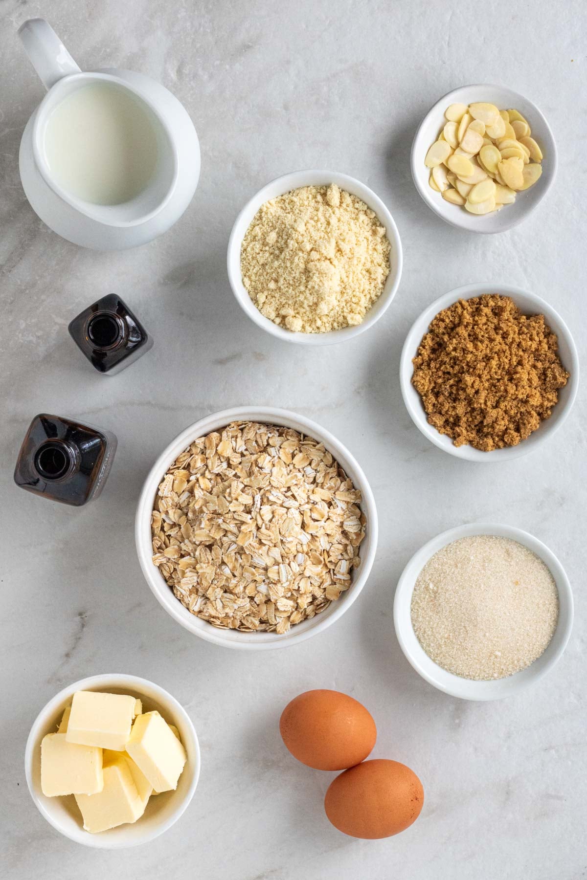 Ingredients for almond croissant baked oats: rolled oats, almond flour, eggs, brown sugar, white sugar, butter, almond extract, vanilla extract, milk, baking powder, salt, and flaked almonds.