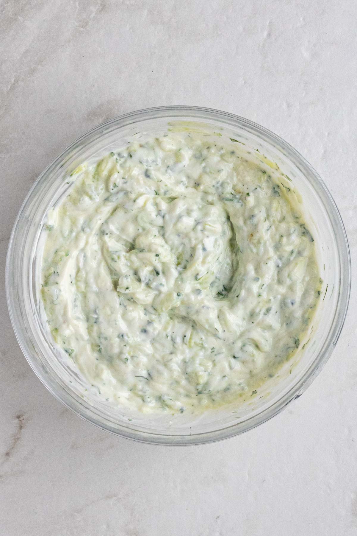 Glass bowl with creamy cucumber yogurt dip.