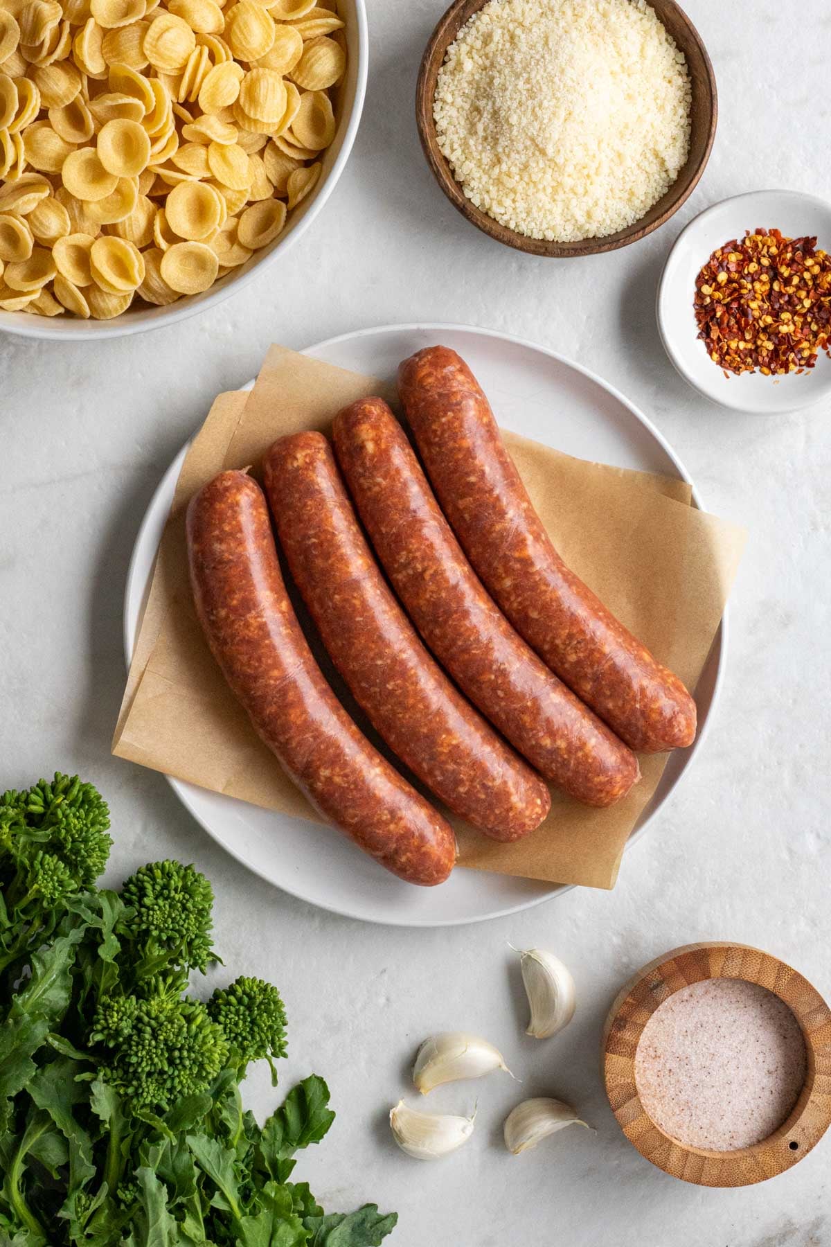 Ingredients for sausage and rapini pasta: orecchiette pasta, spicy Italian sausage, rapini, grated parmesan cheese, garlic, and crushed red pepper flakes.