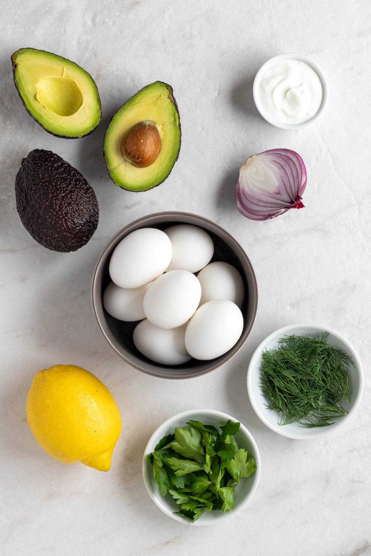 Two ripe avocados, hard-boiled eggs, Greek yogurt, red onion, fresh dill, fresh parsley, and lemon.