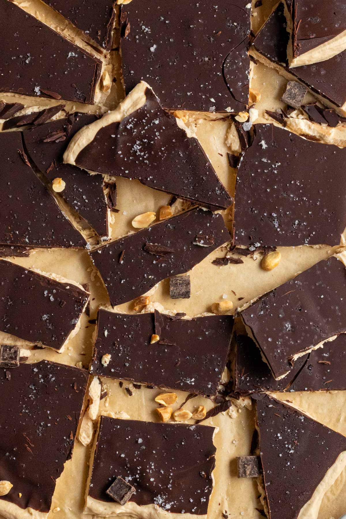 Close of chocolate peanut butter frozen yogurt bark with flaky salt on top on parchment paper.