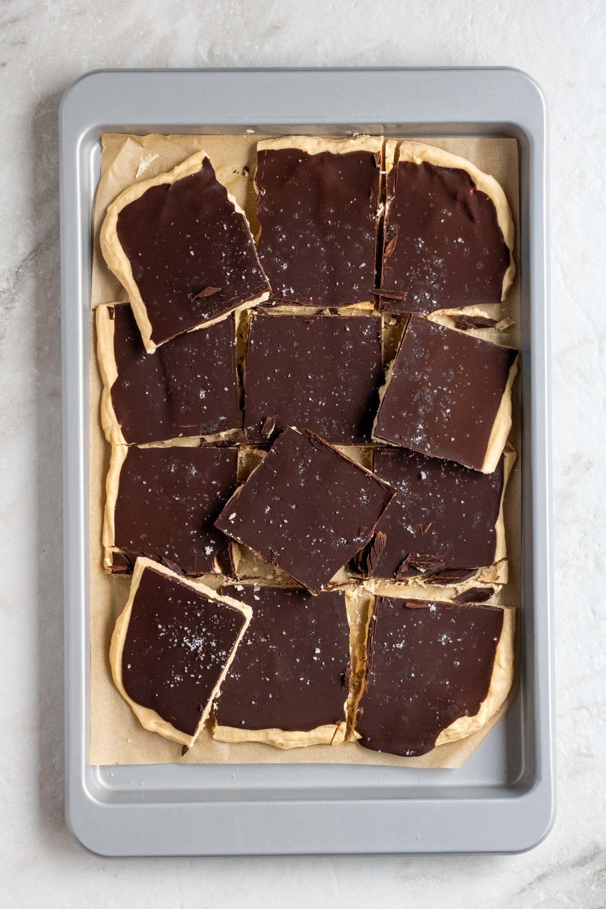 Parchment lined baking sheet chocolate peanut butter frozen yogurt bark with flaky salt broken cut into pieces. 