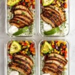 Four Southwest chicken meal prep bowls in glass containers on a white background.