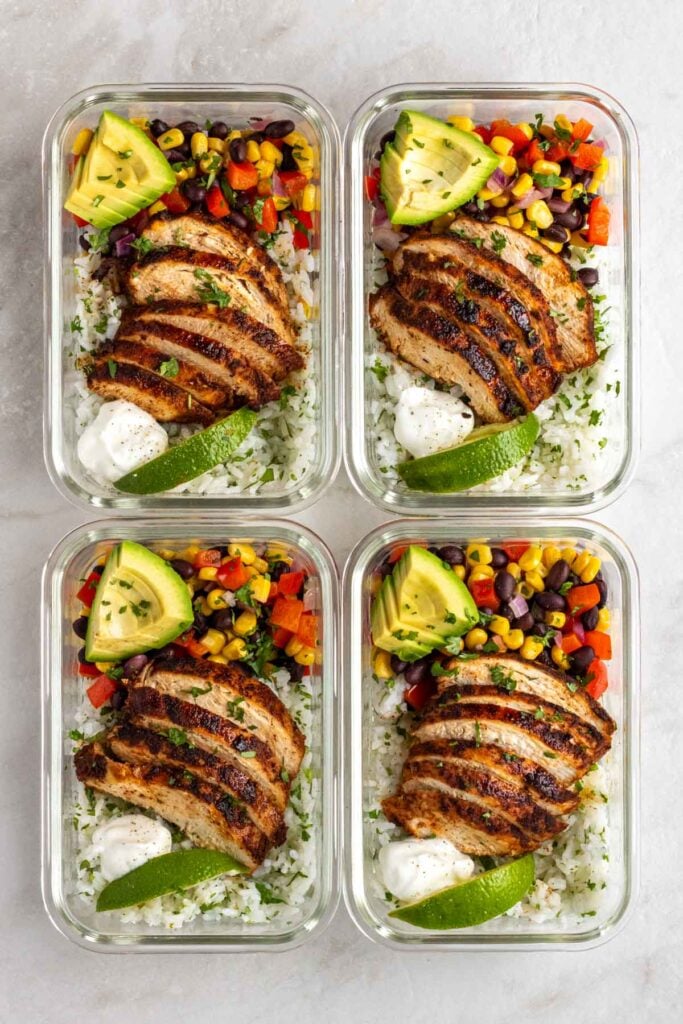 Four Southwest chicken meal prep bowls in glass containers on a white background.