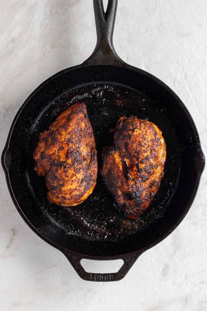 Two cooked Southwest chicken breasts in a cast-iron skillet.
