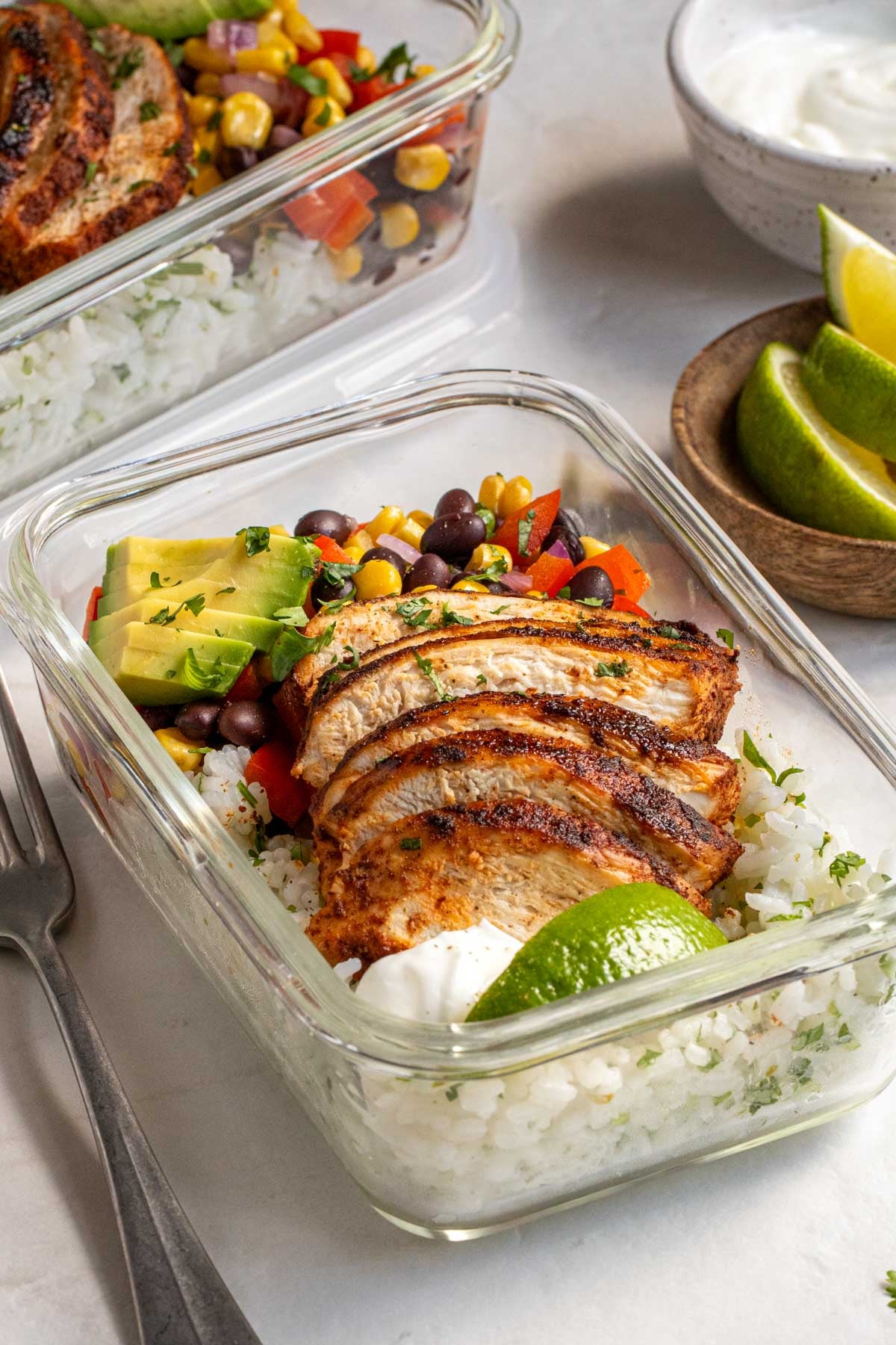Close up of a Southwest chicken bowl in a glass container on a white background.