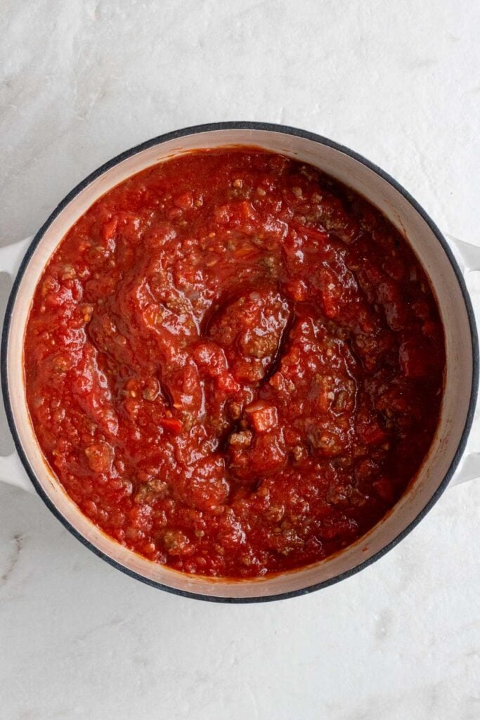 Large pot with cooked meat sauce on a white background.