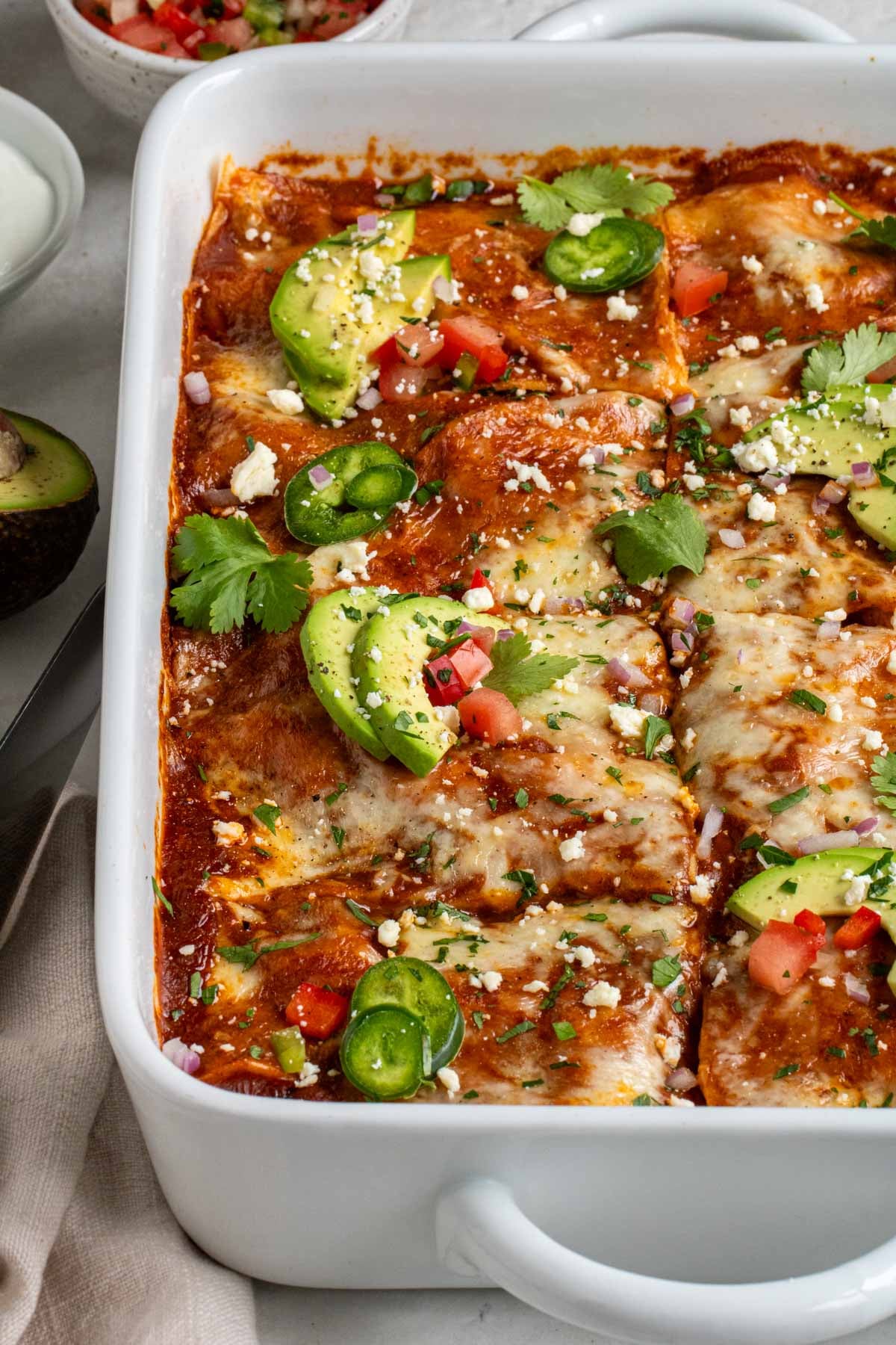 Close up of a large baking dish with slices of chicken enchiladas casserole.