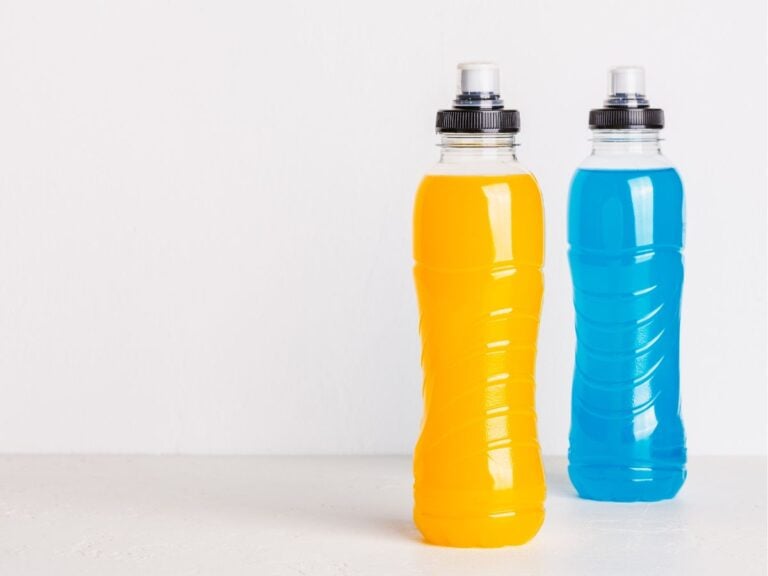 Bottle of orange and blue electrolyte drink on a white background.