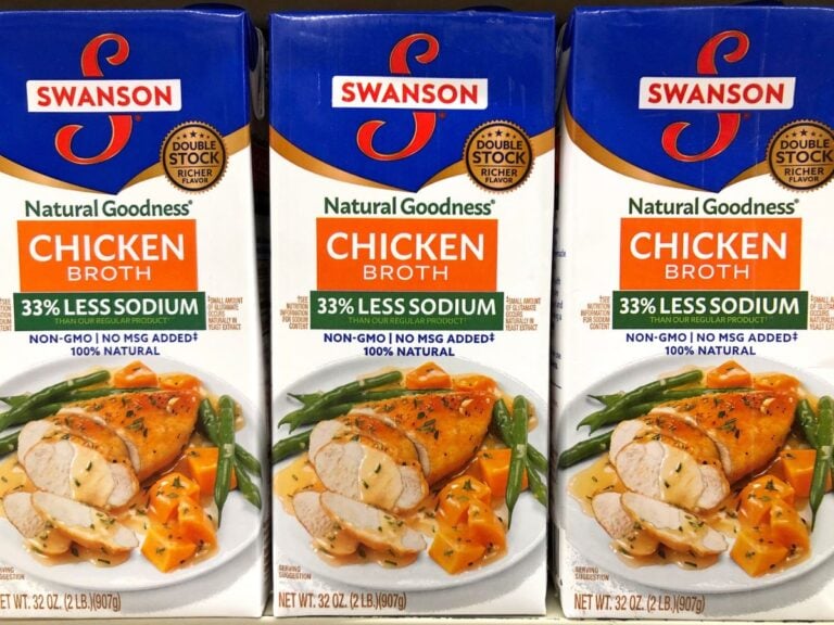 Boxes of low-sodium Swanson chicken broth on a grocery store shelf.