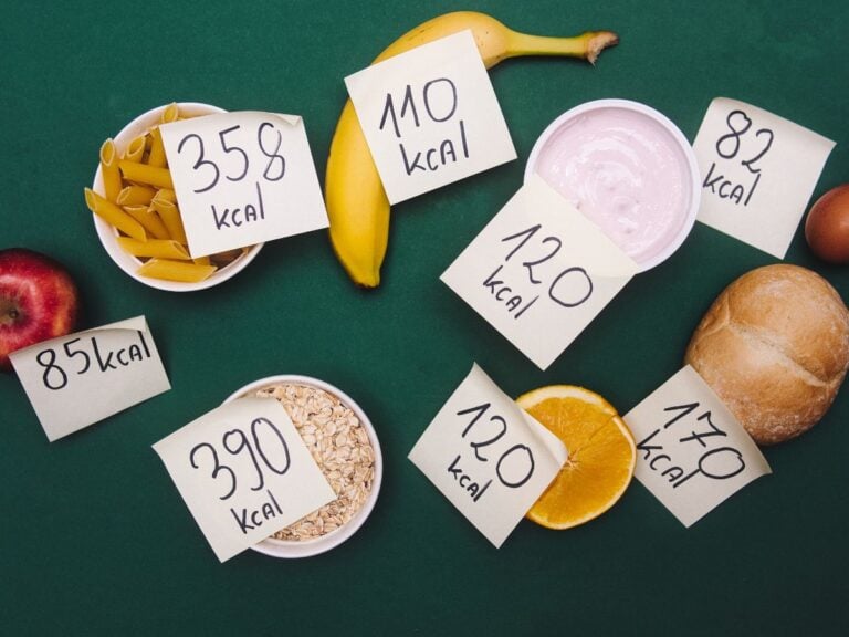 Different foods with a post it note label of the number of calories they contain on a dark green background.