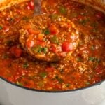 Large pot of stuffed pepper soup with a portion spooned on a ladle.
