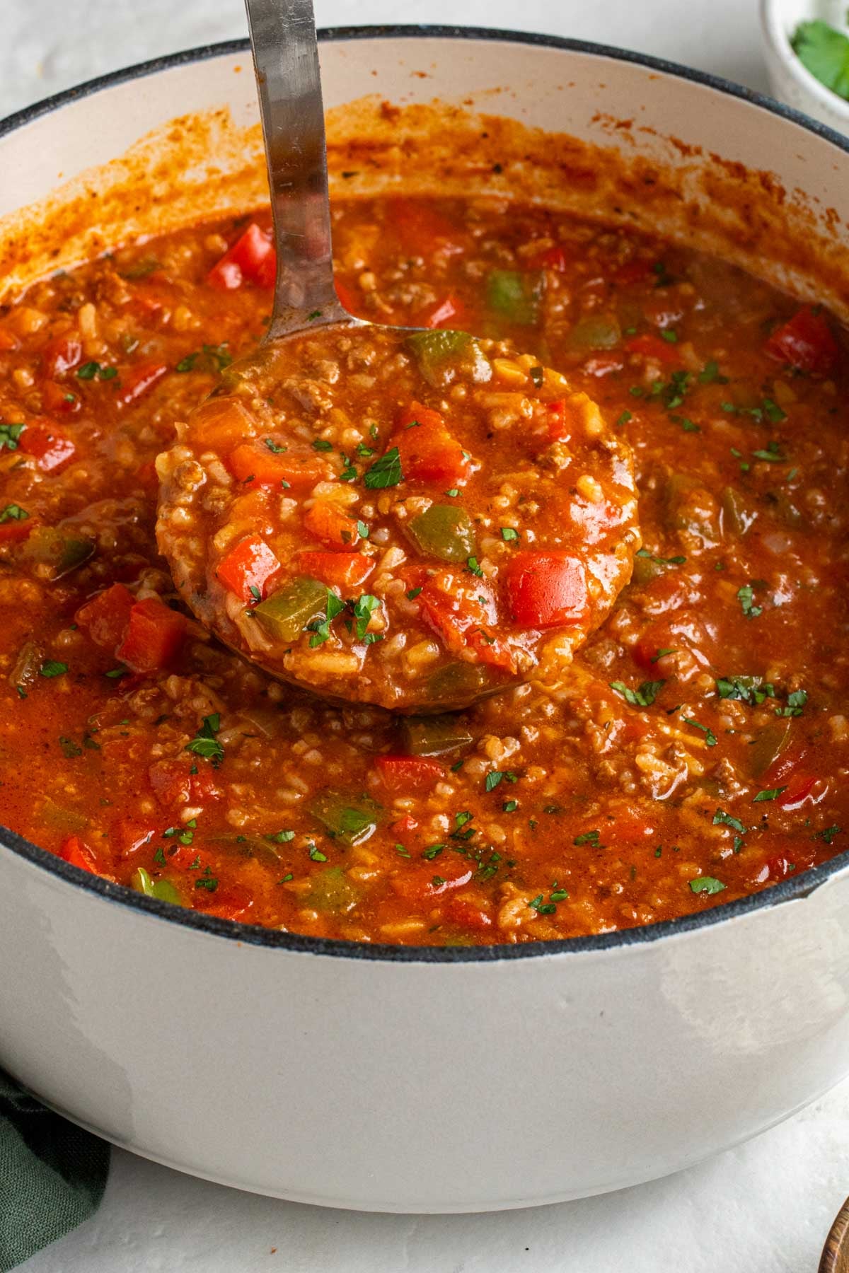 Large pot of stuffed pepper soup with a portion spooned on a ladle.