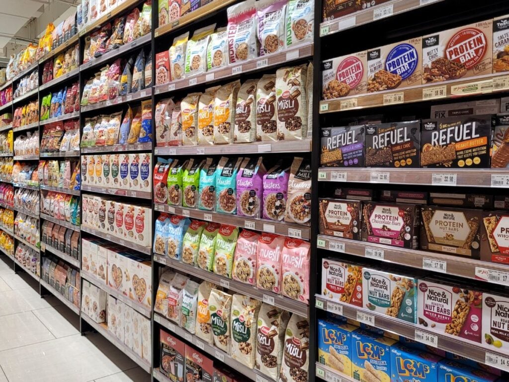 Grocery store shelves filled with protein bars, breakfast cereals, and cookies.
