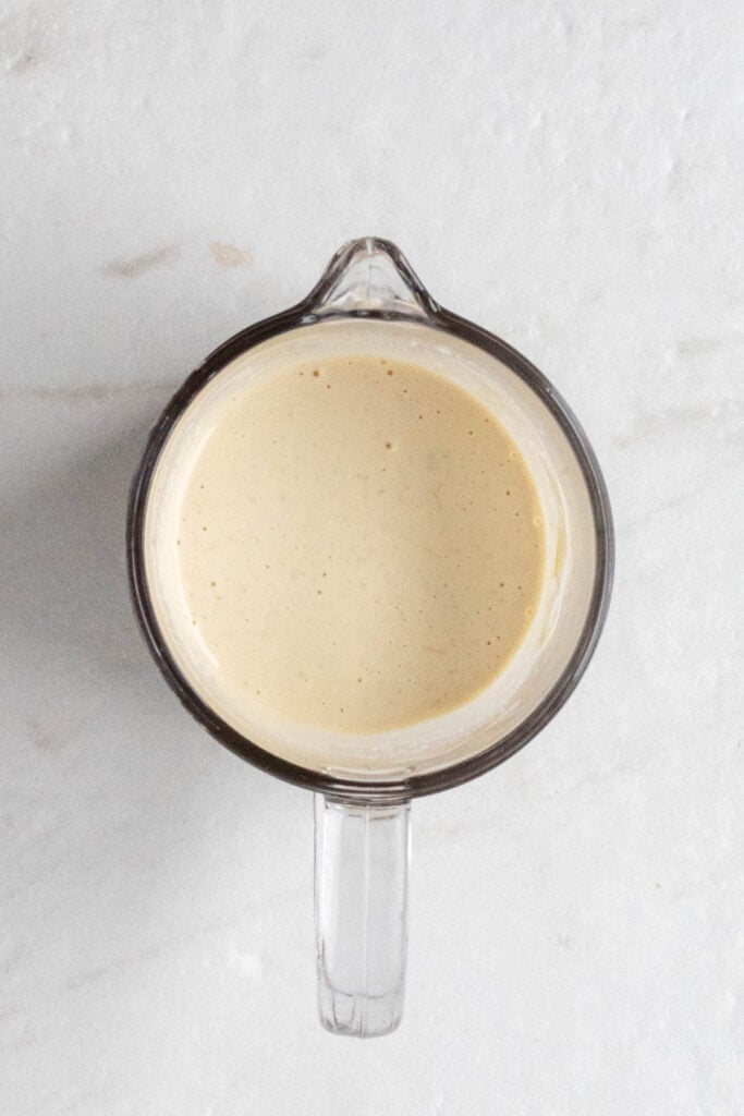 Glass jug of homemade Caesar dressing.