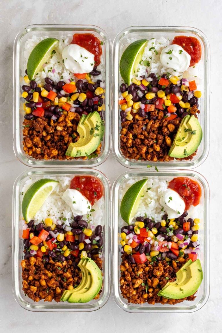 Four meal prep tofu burrito bowls in glass containers on a white background.
