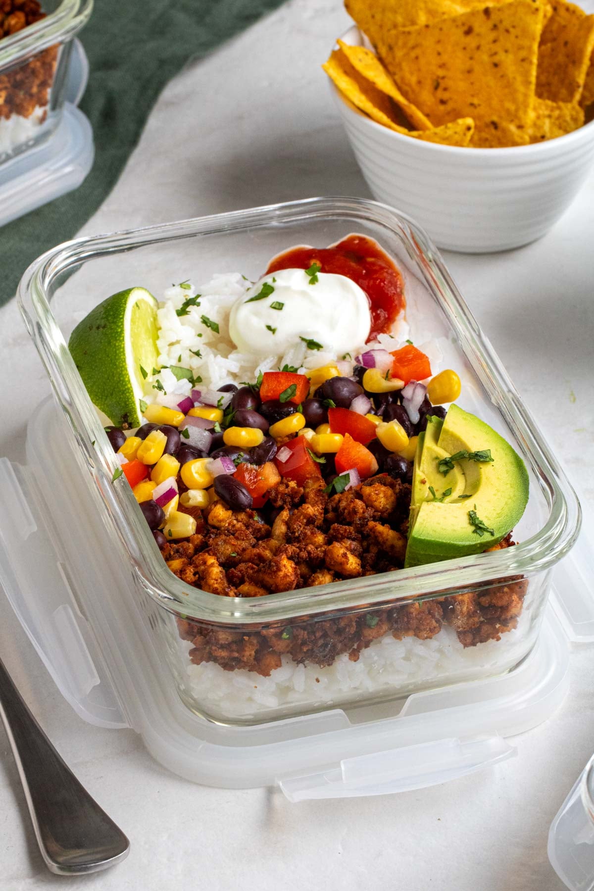 Close up of a vegan burrito bowl with tofu with tortilla chips on the side.