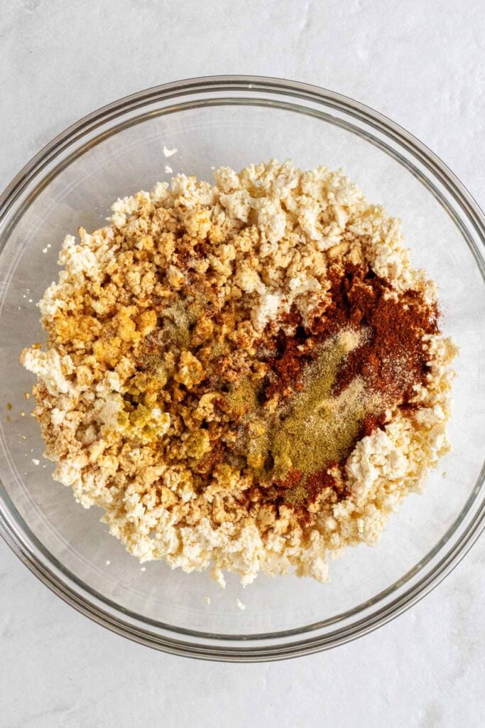 Glass bowl with crumbled tofu and spices on top.