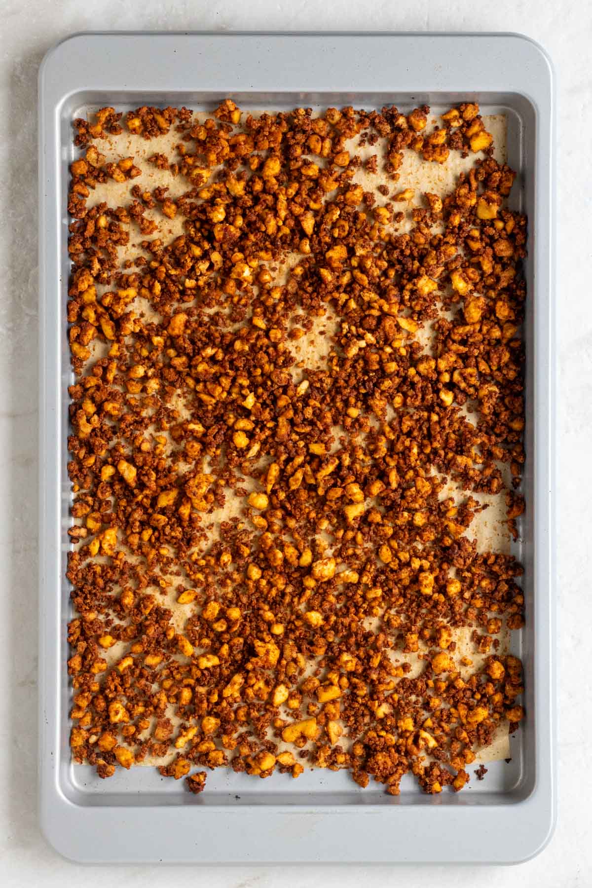 Large baking sheet with parchment paper on top with cooked crumbled tofu meat.