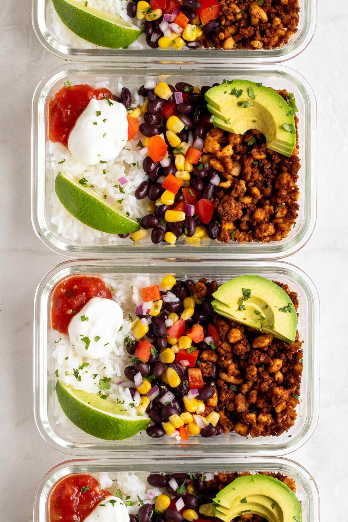 Glass meal prep contains of tofu burrito bowls organized in a vertical line.