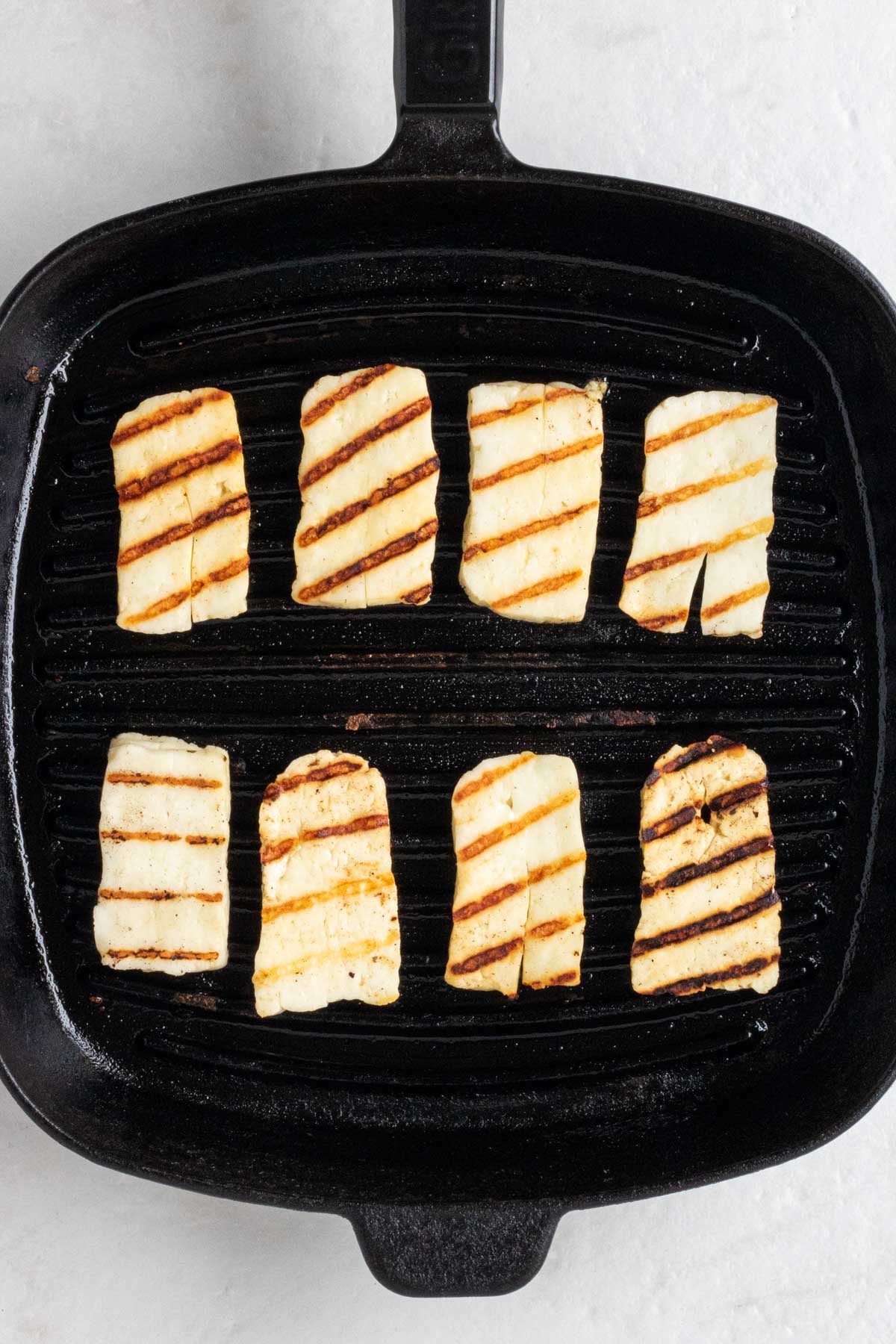 Slices of grilled halloumi cheese in a grill pan.