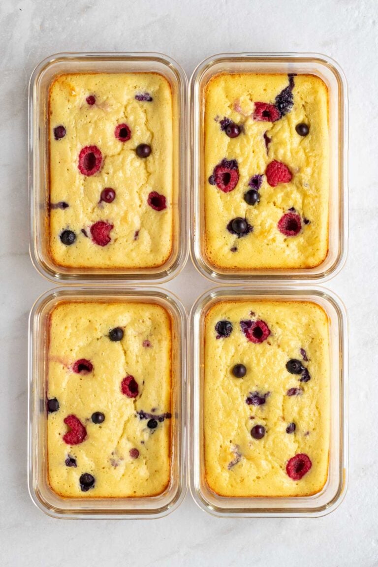 Four protein pancake bowls in glass meal prep containers on a white background.