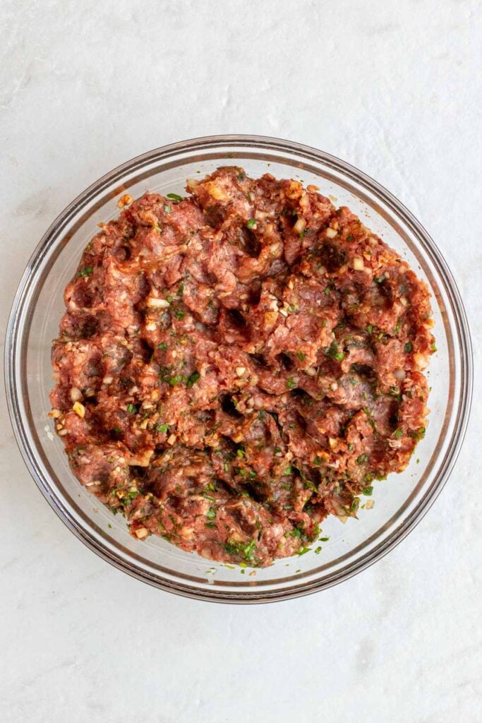 Glass bowl with beef mixture on a white background.