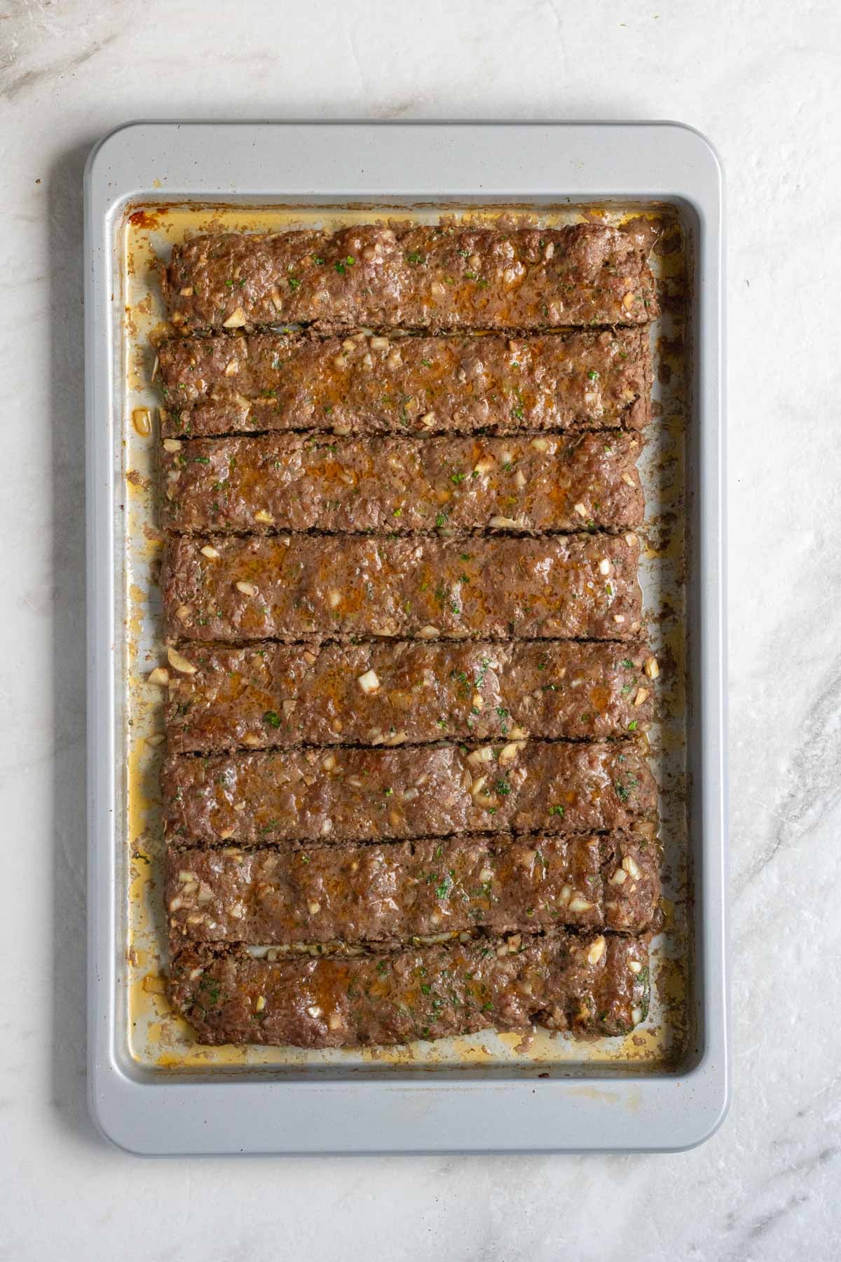 Slices of beef kebabs on a sheet pan.