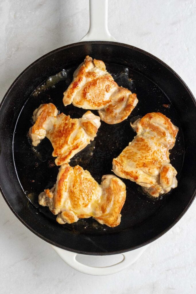 Large pan with cooked chicken thighs.