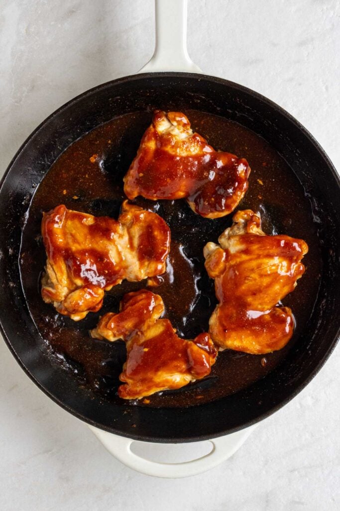 Large pan with cooked chicken thighs covered in homemade teriyaki sauce.
